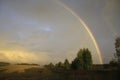 A bright rainbow over a field and copses after an autumn rain at sunset. Autumn bad weather in the foothills of the Western Urals. Royalty Free Stock Photo