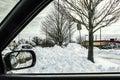 Looking out car window at piled up snow drifts and a convenience store in the distance with rear view window showing more snow Royalty Free Stock Photo