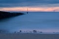 Sunrise at the sea shore with sea defenses and off shore wind farm