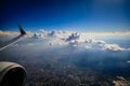 Looking out the window of an airplane to see a wingtip, engine and bright fluffy clouds and a deep blue sky