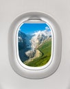 Looking out the window of a plane to the mountains and glacier Royalty Free Stock Photo