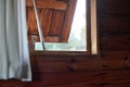 Looking out wooden window on beach house, opened just a little bit, blurred bright landscape outside