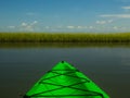 Looking over the bow of a bright green kayak at calm flat water