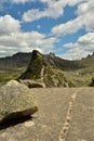 Looking over large rocks at a narrow hiking trail that runs along the top of a spiky mountain on a cloudy summer day Royalty Free Stock Photo