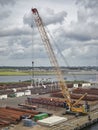 Looking over a Quay filled with Pipework of Varying sizes and other equipment going to be used in a Maritime Setting.