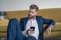 Looking perfect. Handsome young man in full suit using his cell phone while sitting on the floor at home Royalty Free Stock Photo
