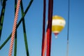 Looking through ropes of a balloon on a blurred yellow balloon in the background in front of blue sky Royalty Free Stock Photo