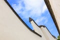 Looking skyward in a hutong alley between two white traditional brick concrete walls and tiles