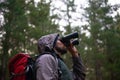 Looking for that special bird. Handsome man using his binoculars to scan the surrounding forest for bird life. Royalty Free Stock Photo