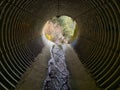 Looking thought a drain tunnel under a road with a little water Royalty Free Stock Photo