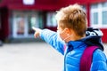 Looking to school Attractive schoolboy in protective mask standing outdoor child points finger at school close up Royalty Free Stock Photo