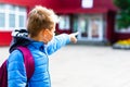 Looking to school Attractive schoolboy in protective mask standing outdoor child points finger at school close up Royalty Free Stock Photo