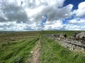 Hikers path, running alongside a dry stone wall with, Cowling Pinnacle in the distance in, Cowling, UK