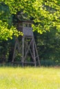 Looking through tree branches pass the meadow with hunting blind in background Royalty Free Stock Photo