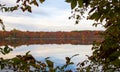 Looking through the trees at autumn colored leaves reflecting in a lake