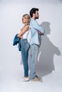 Looking trendy. Full length of beautiful young couple standing back to back against grey background