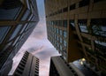 Looking up at beautiful dusk pink blue summer sunset sky surrounded by tall high rise tower block sky scrapers. Royalty Free Stock Photo