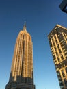 Looking up at the Empire State Building at the golden hour, warm light illuminates the iconic Art Deco skyscraper in midtown