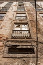 Looking up facade with ocher sand walls and broken windows Iron bars in front of the windows and broken washing line in Lisbon