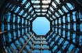 Looking up from inside old gasometer structure with metal framework reaching towards clear blue sky. Geometric patterns of steel Royalty Free Stock Photo