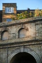 Looking up at old brick wall and archway with house and windows in background Royalty Free Stock Photo