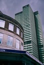 Looking up at outside of London underground station with modern office block Royalty Free Stock Photo