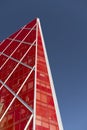 Looking up at shiny red modern and contemporary office building against a blue sky