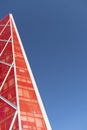 Looking up at shiny red modern and contemporary office building against a blue sky