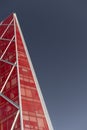 Looking up at shiny red modern and contemporary office building against a blue sky