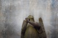 Looking up at a statue of a Victorian graveyard angel. Holding hands together in prayer. With a grunge, vintage, old edit