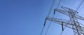 Looking up steel power pylon construction with high voltage cables against blue sky. Wide banner for electric energy Royalty Free Stock Photo