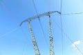 Looking up tall steel power pylons with electric cables against blue sky