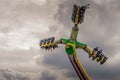 Looking up at thrill-seekers on a fairground ride against a dramatic cloudy sky