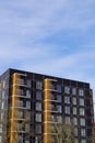 Looking up to the black new modern building with brown, yellow, orange details. Balconies with wooden planks details Royalty Free Stock Photo