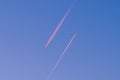 Looking up at two passenger airplanes flying in opposite direction parallel to each other in red glowing evening sun and blue sky