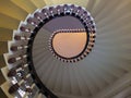 Ooking upwards view of an elegant spiral staircase with wooden bannisters in elegant shades of white Royalty Free Stock Photo