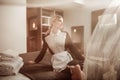 Blonde-haired hotel maid sitting on bed and looking into window