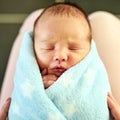 He looks so comfortable. a tired little baby boy sleeping with his eyes closed while his mother holds him in her hands Royalty Free Stock Photo