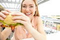 This looks delicious. Portrait of a pretty young woman eating a massive, delicious burger at a restaurant.