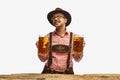 Portrait of young cheerful man in hat, wearing traditional Bavarian clothes, holding beer mug isolated white background Royalty Free Stock Photo