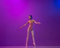 Studio shot of beautiful school age girl, ballet dancer dancing  on purple background in neon light. Art, grace Royalty Free Stock Photo