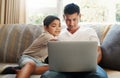 That looks like a cool game. a handsome young man sitting on the sofa and bonding with his son while using a laptop.