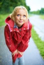 Looks like the rain isnt going to stop...Gorgeous young blonde woman wearing a red raincoat in the rain outdoors on a