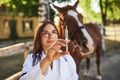 Looks at syringe. Female vet examining horse outdoors at the farm at daytime Royalty Free Stock Photo
