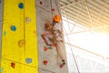 Lookup view a boy climbing a indoor cliff with sun flare background