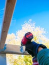 Lookup view hand man using cordless impact driver fasten attach exterior wood screws to galvanized joist hanger support underneath