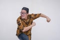 A looney middle aged man about to run in a comical fashion. Exiting the stage in a funny way. Wearing a batik shirt and songkok