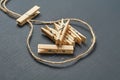 Loop of rope with heap of wooden clothespins in center on background of dark concrete