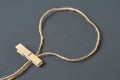Loop of rope with one wooden clothespin on background of dark concrete. Space for text Royalty Free Stock Photo
