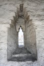 A loophole in the darkened soot-covered white brick wall of a medieval fortress